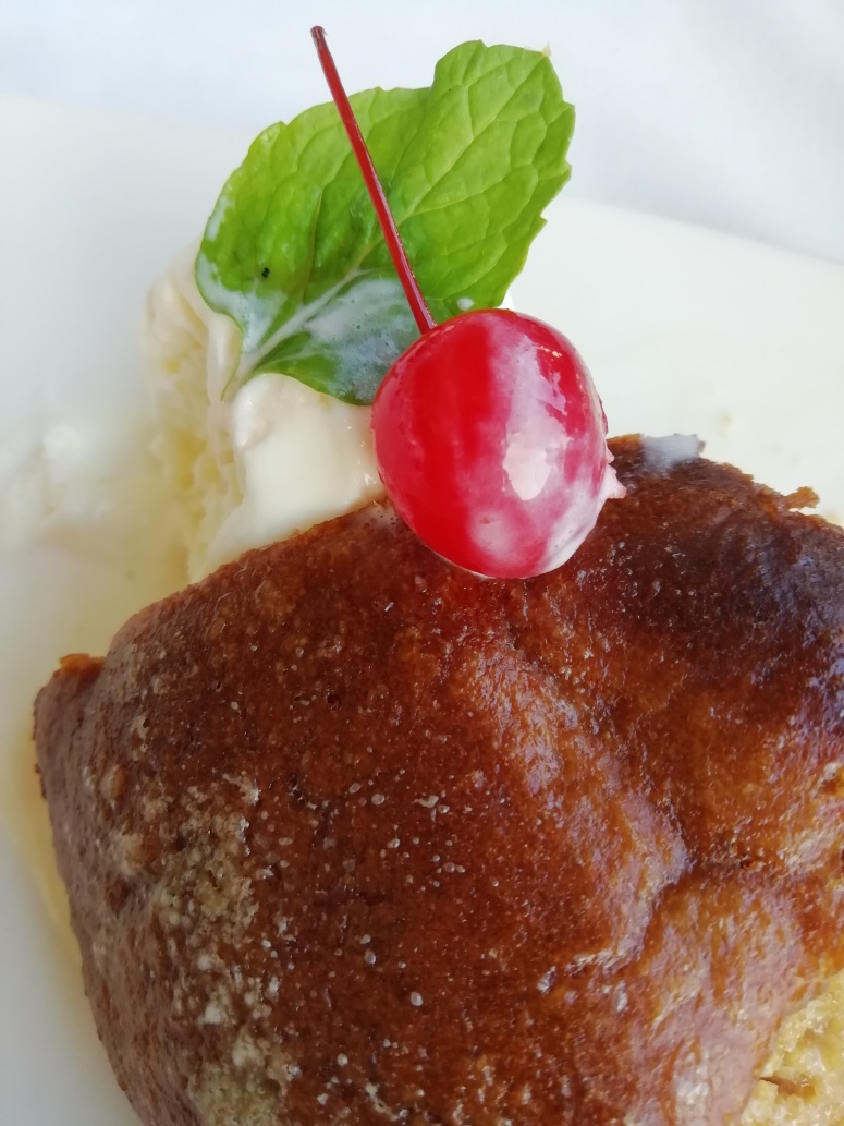 malva pudding with vanilla ice cream and a red cherry